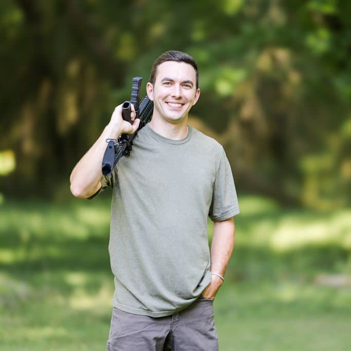 Jesse outdoors with a rifle over his shoulder